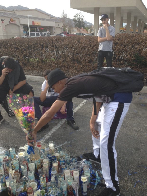 Friends gather around a memorial set up in the parking lot of a north Moreno Valley fast-food restaurant in honor of the Asencio brothers on Friday, March 9, 2018. (Photo by David Downey, Staff)